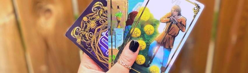 A person holds tarot cards in their hand.