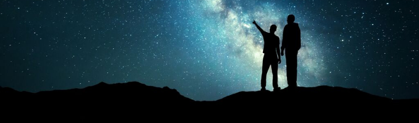 A silhouetted figure stands among the night sky. The stars are visible.